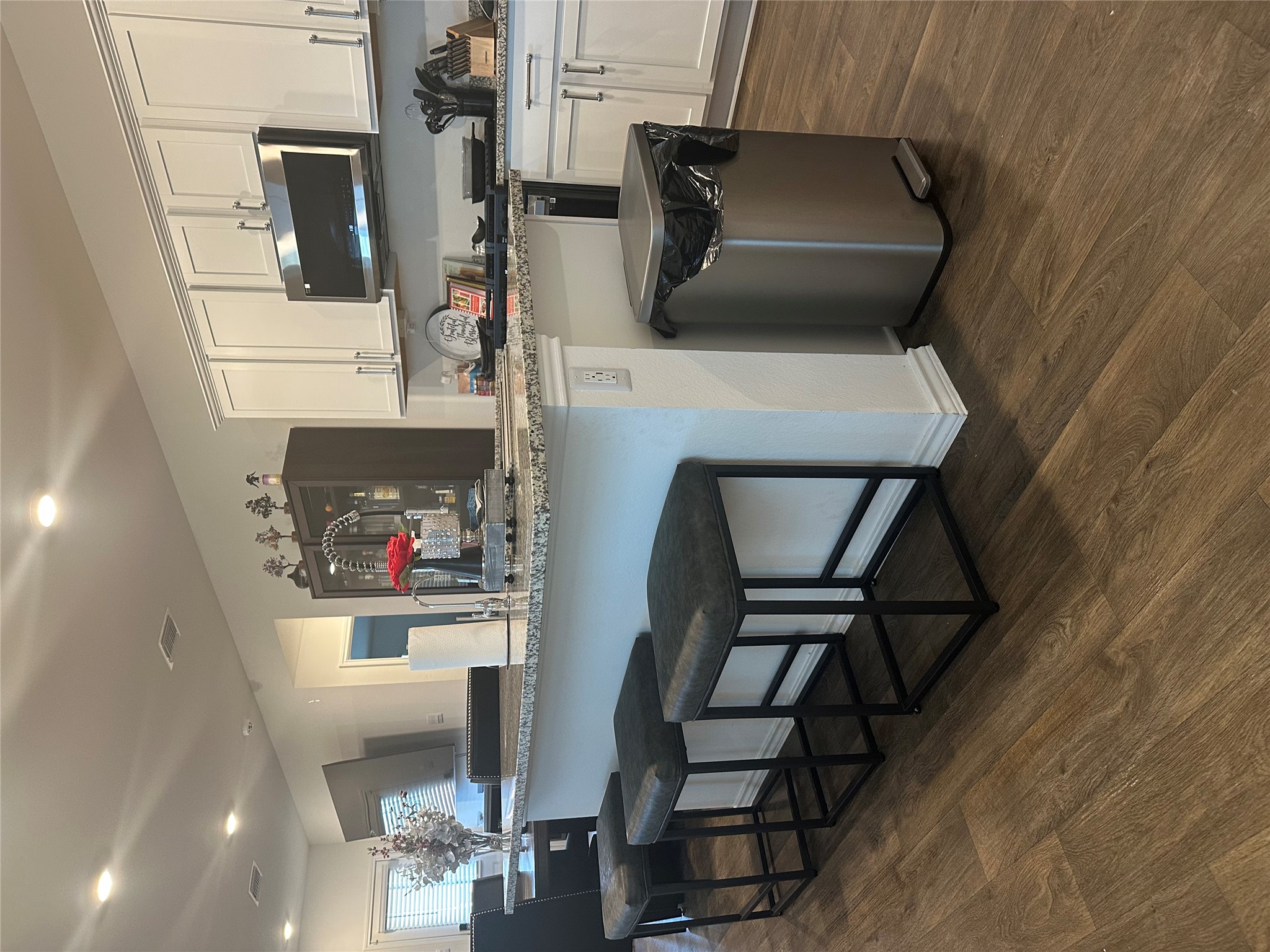 519 Sandringham Loop Kyle, TX 78640 - Photo 15 of 26 Kitchen featuring white cabinetry, stainless steel microwave, light stone countertops, a kitchen bar, and recessed lighting