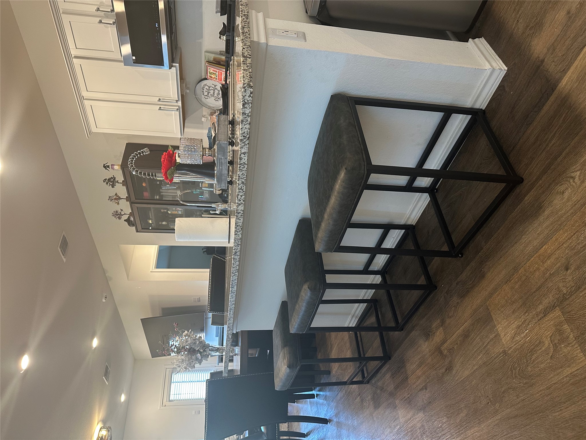 519 Sandringham Loop Kyle, TX 78640 - Photo 16 of 26 Kitchen with white cabinetry, a breakfast bar, stainless steel microwave, dark wood-style flooring, and light stone countertops
