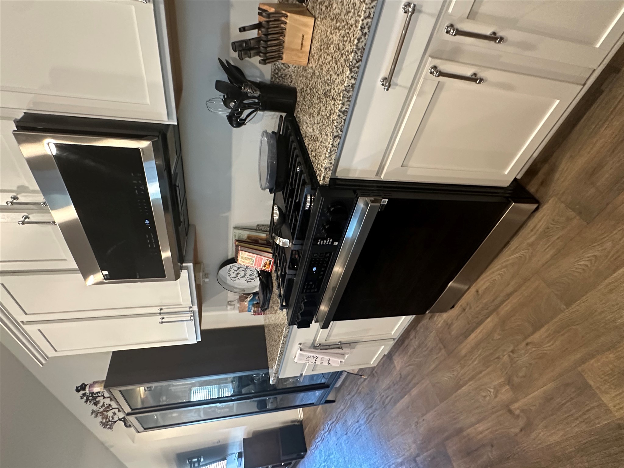 519 Sandringham Loop Kyle, TX 78640 - Photo 23 of 26 Kitchen featuring gas range oven, stainless steel microwave, light stone countertops, white cabinets, and dark wood-style floors