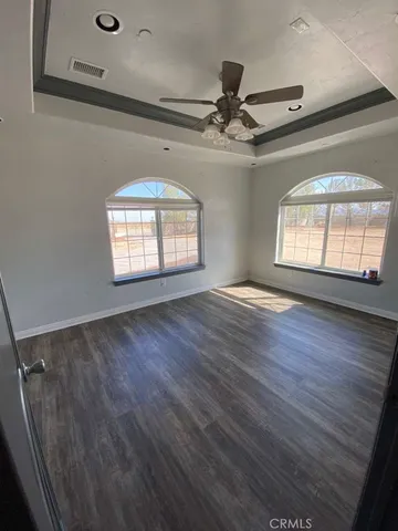 a view of empty room with wooden floor and fan