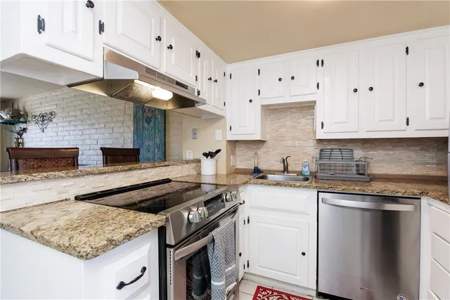 a kitchen with granite countertop a stove sink and cabinets