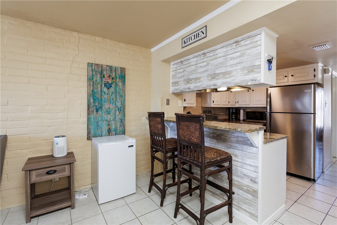 15432 Salt Cay Court, Unit 101 Corpus Christi, TX 78418 - Photo 6 of 37 a kitchen with stainless steel appliances granite countertop a stove a refrigerator a dining table and chairs with wooden floor