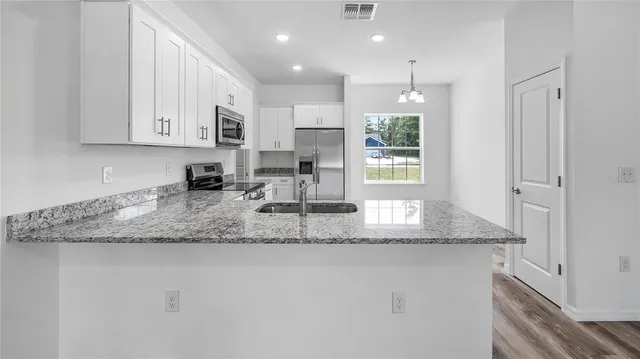 a kitchen with granite countertop kitchen island white cabinets and stainless steel appliances