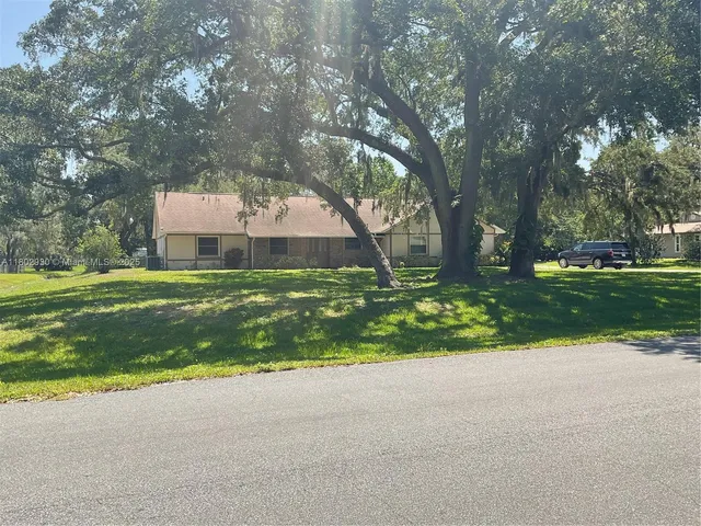a view of a house with a big yard and large trees