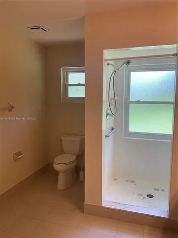 a bathroom with a granite countertop toilet and a shower