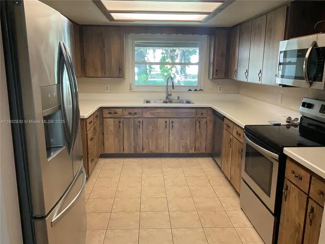 a kitchen with a sink a refrigerator and window
