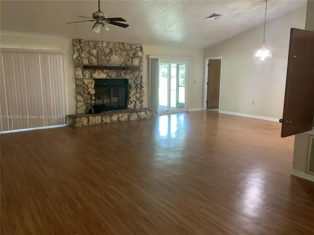 an empty room with wooden floor fireplace and windows