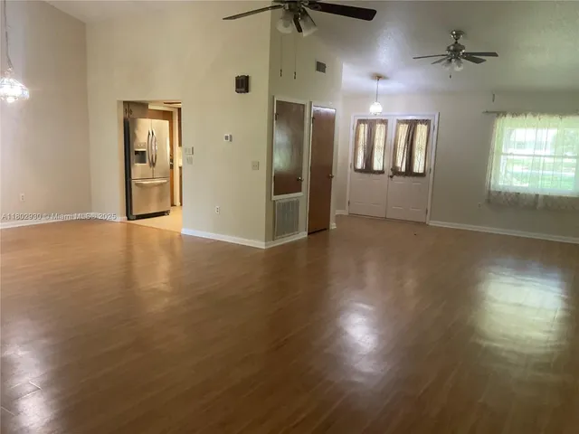 a view of an empty room with window and wooden floor
