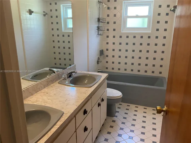 a bathroom with a granite countertop sink a toilet and shower