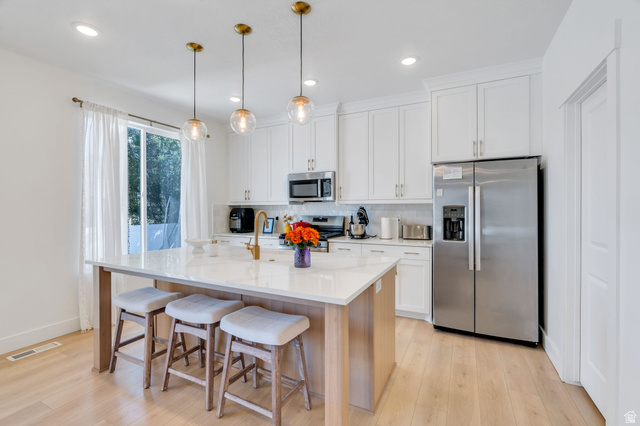 2664 West Maple Street Mapleton, UT 84664 - Photo 15 of 49 Kitchen featuring a central island with countertop seating, white cabinetry, stainless steel appliances, and wood-finish flooring