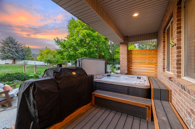 6208 West Bull River Road Highland, UT 84003 - Photo 60 of 90 Covered patio featuring a built-in spa, composite decking, integrated wooden bench seating, and a brick exterior