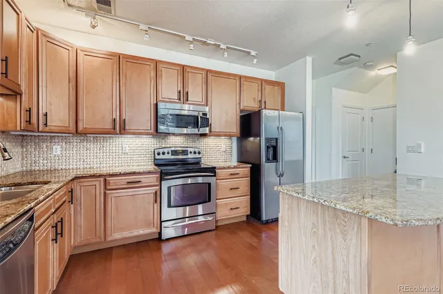 a kitchen with stainless steel appliances granite countertop a refrigerator a stove top oven a sink and dishwasher