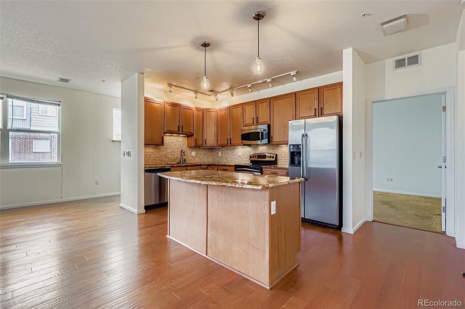 11316 Colony Circle Broomfield, CO 80021 - Photo 4 of 20 a kitchen with stainless steel appliances granite countertop a refrigerator a sink dishwasher a oven a dining table and chairs with wooden floor