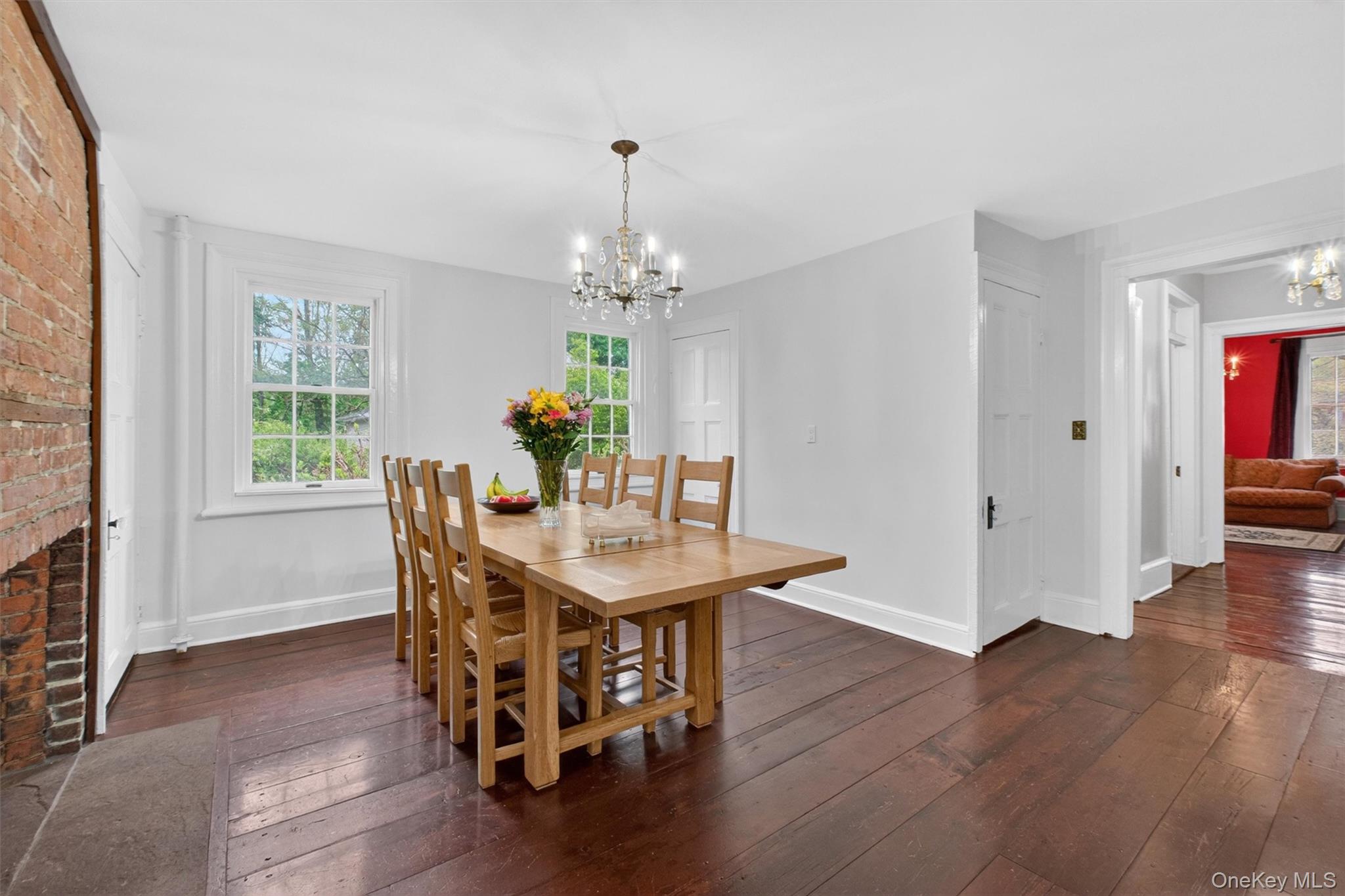 121 Old Glenham Road Fishkill, NY 12524 - Photo 16 of 50 Dining room featuring a prominent exposed brick fireplace, hardwood flooring, large windows and a doorway leading other living areas.
