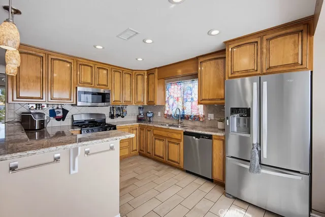 a kitchen with granite countertop stainless steel appliances a refrigerator sink and microwave