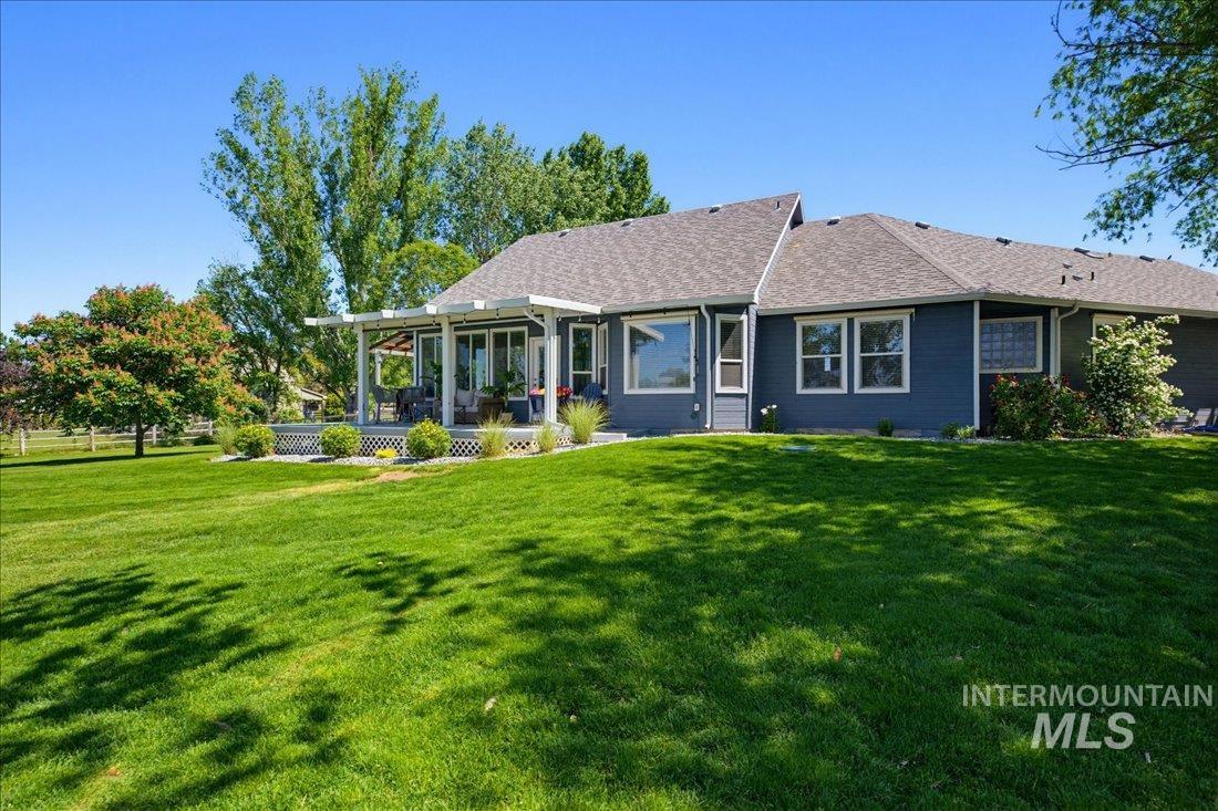 24623 Falcon Lane Caldwell, ID 83607 - Photo 26 of 40 Expansive green lawn bordering a single-story residence with dark blue siding and a multi-pitch roof