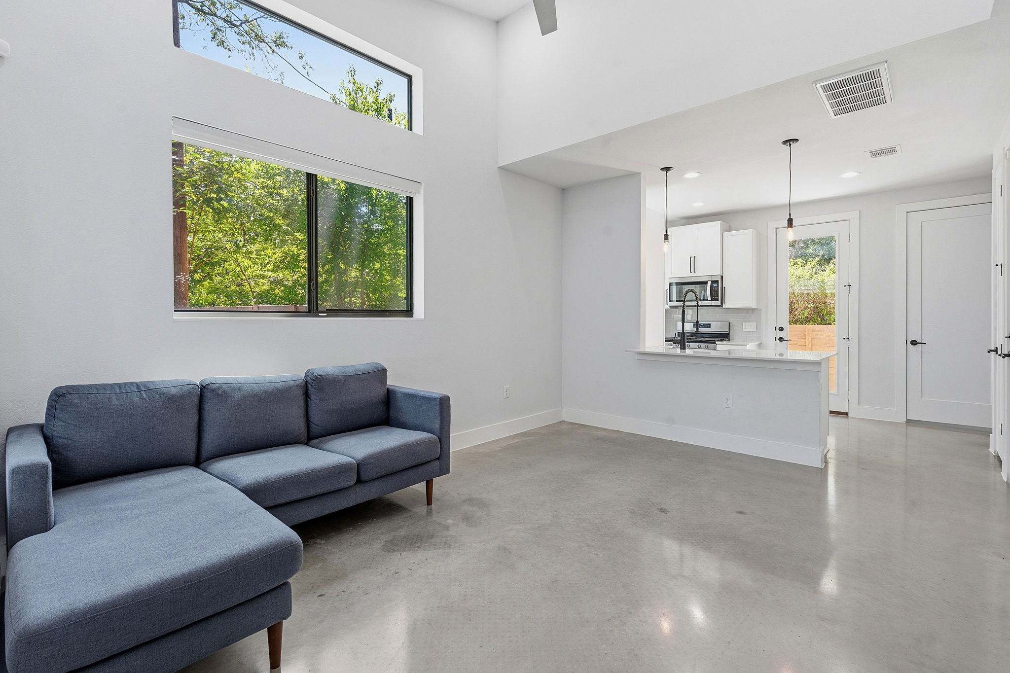 2935 Moss Street, Unit 2 Austin, TX 78722 - Photo 5 of 20 High ceilings and large windows define this luminous living space, seamlessly integrating with the compact kitchen.
