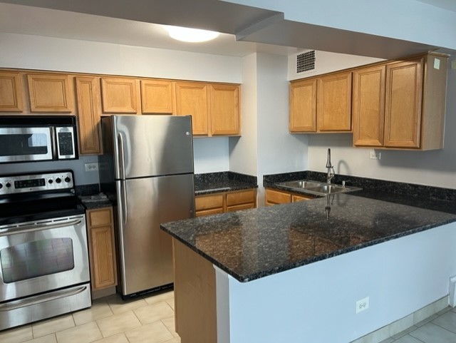 6030 North Sheridan Road, Unit 1712 Chicago, IL 60660 - Photo 7 of 28 a kitchen with granite countertop a refrigerator a sink and wooden cabinets