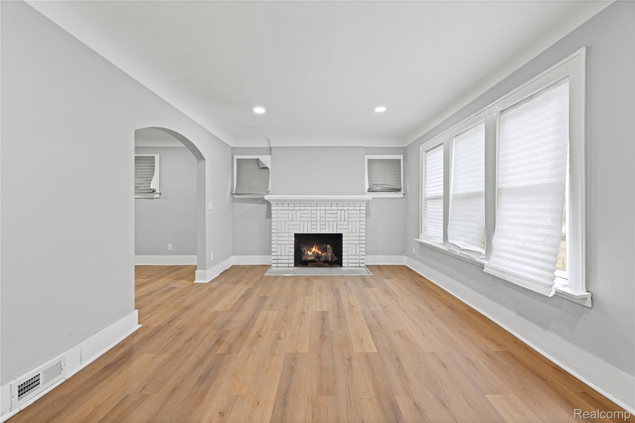 9175 Devonshire Road Detroit, MI 48224 - Photo 3 of 26 White brick fireplace with mantel, wood-finish flooring, recessed lighting, and arched doorway