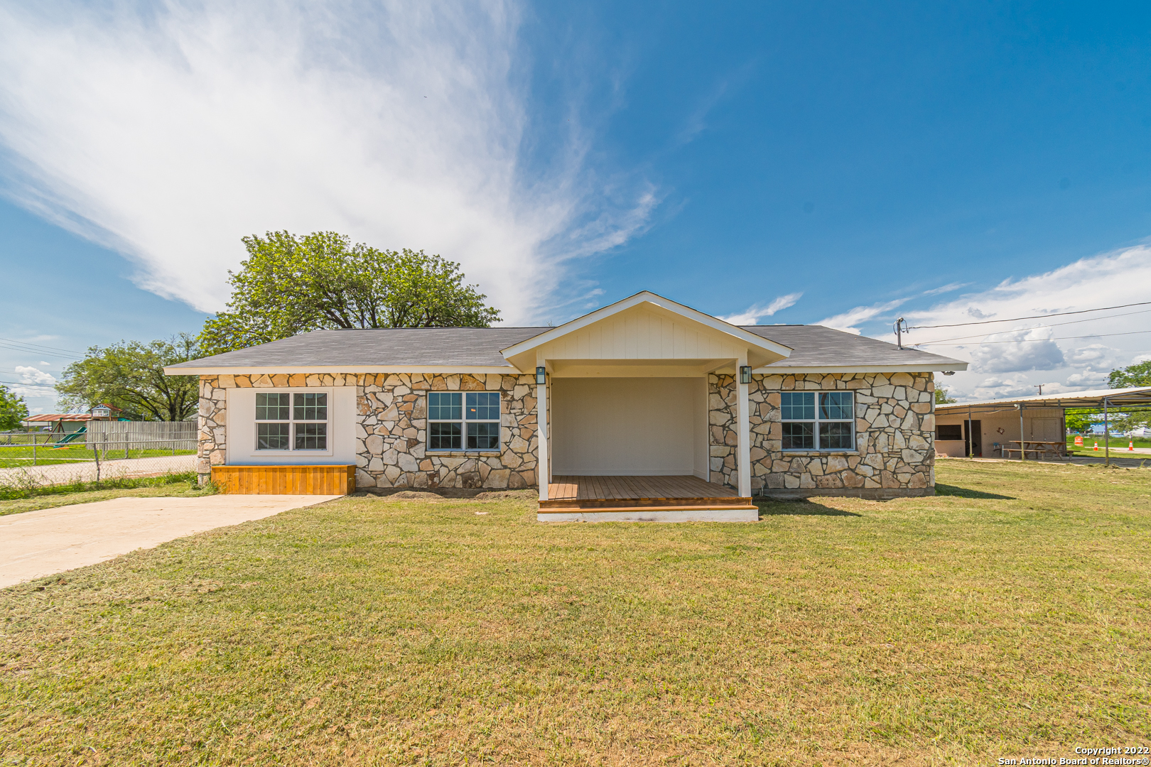 715 Walnut Street Jourdanton, TX 78026 - Photo 1 of 1 a view of a house next to a big yard with large trees