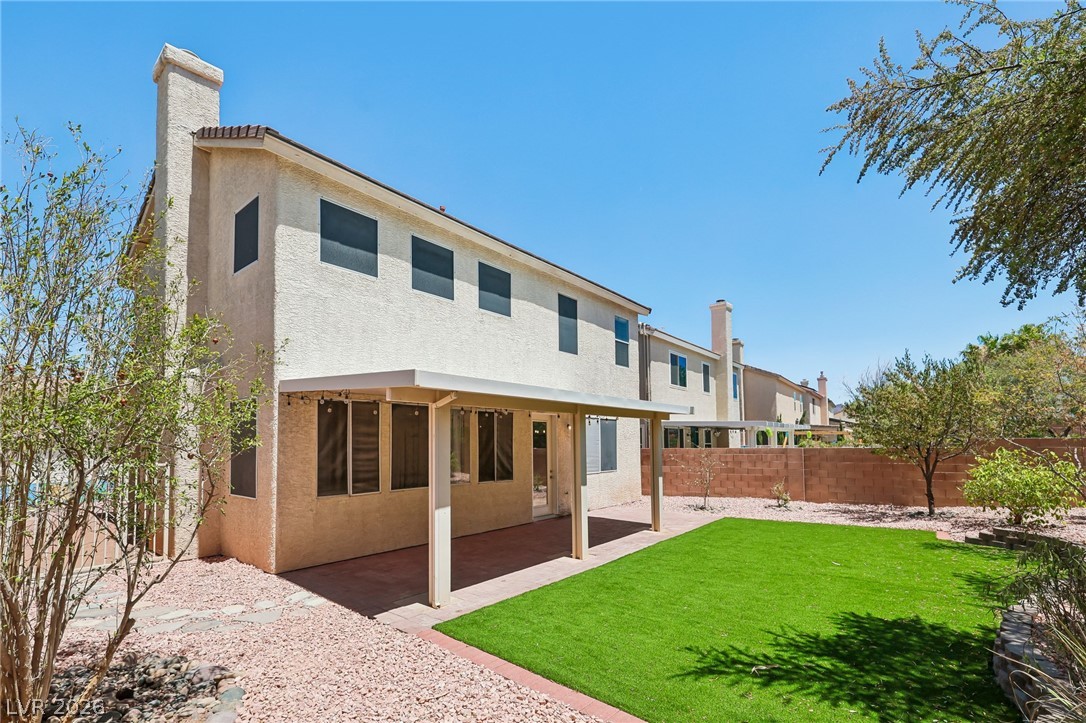 1727 Millstream Way Henderson, NV 89074 - Photo 5 of 46 A private backyard oasis features an artificial turf lawn and a covered patio, ideal for outdoor living.