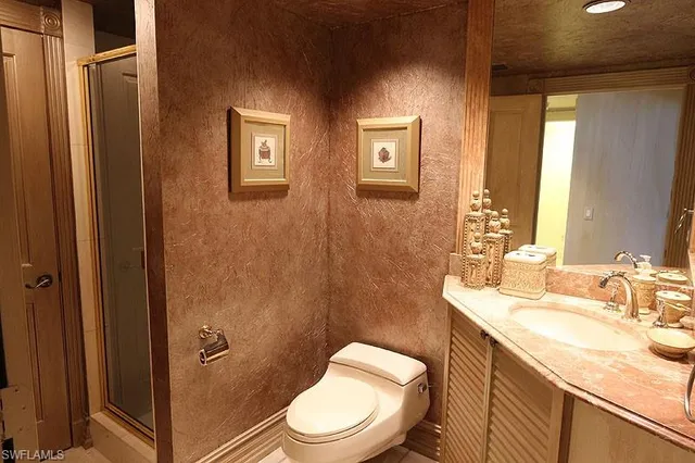 a bathroom with a granite countertop toilet sink and mirror