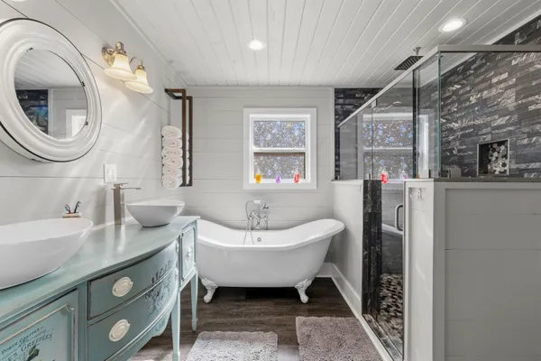 a spacious bathroom with a sink a mirror a bathtub and a window