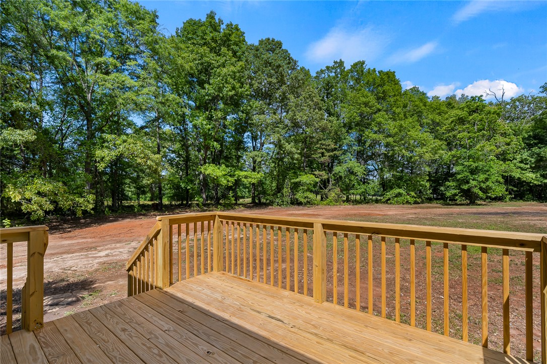 131 Lockaby Road Pelzer, SC 29669 - Photo 4 of 50 This spacious wooden deck offers serene views of lush surrounding trees and a clear blue sky.