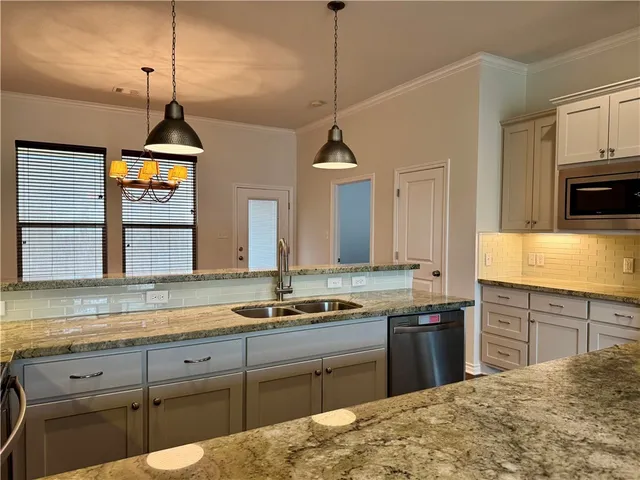 a kitchen with granite countertop a sink a stove and cabinets