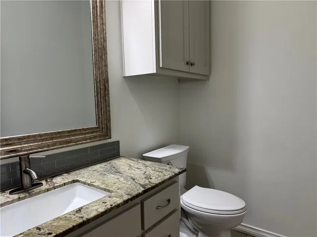 a bathroom with a granite countertop toilet sink and mirror