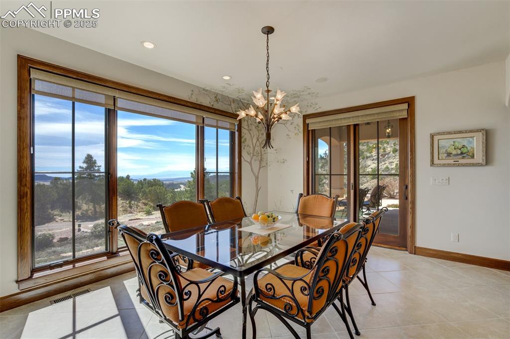 14250 Aiken Ride View Colorado Springs, CO 80926 - Photo 23 of 50 a dining room with furniture large windows and a chandelier