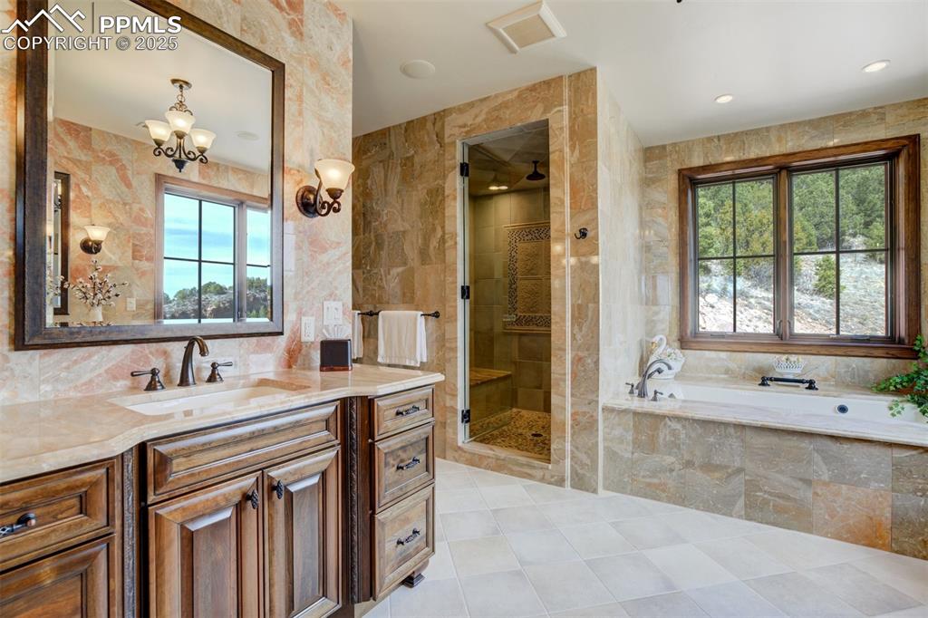 14250 Aiken Ride View Colorado Springs, CO 80926 - Photo 37 of 50 a spacious bathroom with a double vanity sink a mirror a bathtub and next to a window