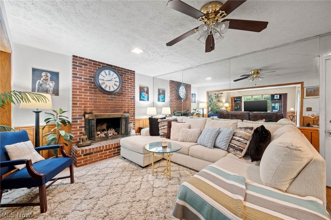439 South Miller Road Akron, OH 44313 - Photo 14 of 31 Living room featuring a fireplace, brick wall, a textured ceiling, and ceiling fan