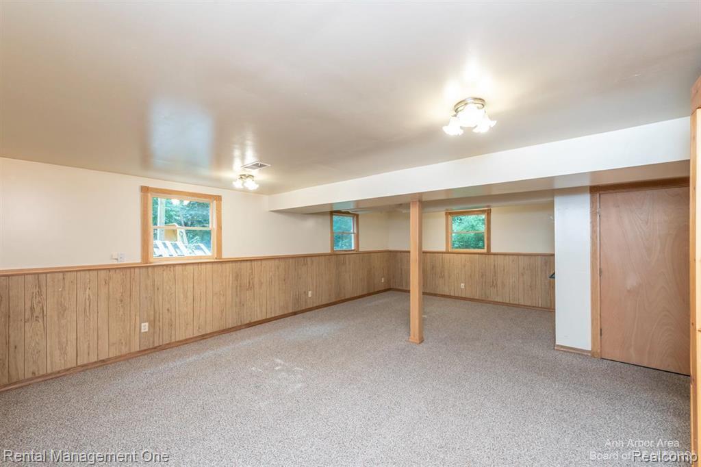 7870 Chamberlin Road Dexter, MI 48130 - Photo 37 of 52 Spacious room featuring neutral carpeting, wood-paneled wainscoting, and multiple windows