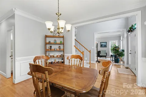 a dining room with wooden floor a chandelier a wooden table and chairs