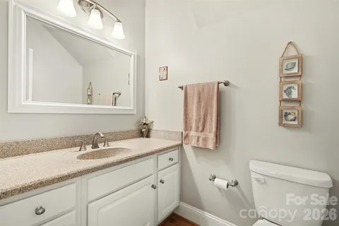 a bathroom with a granite countertop toilet sink and mirror