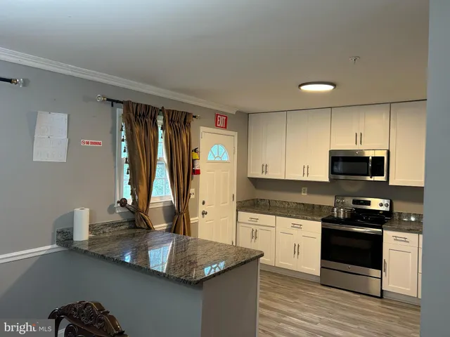 a kitchen with kitchen island granite countertop a sink appliances cabinets and a counter top space