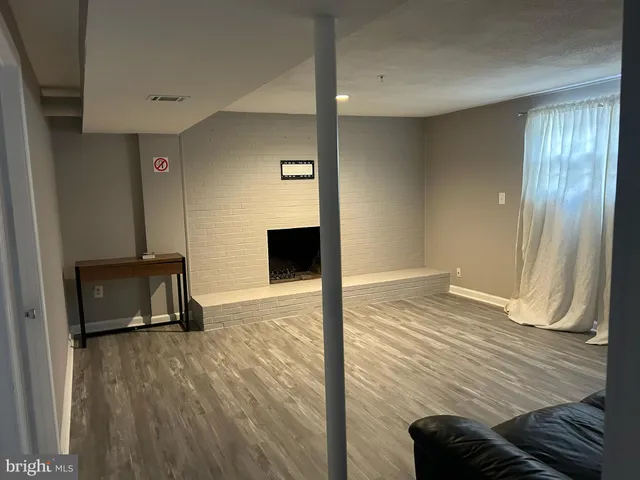 a view of a livingroom with wooden floor and a bathroom