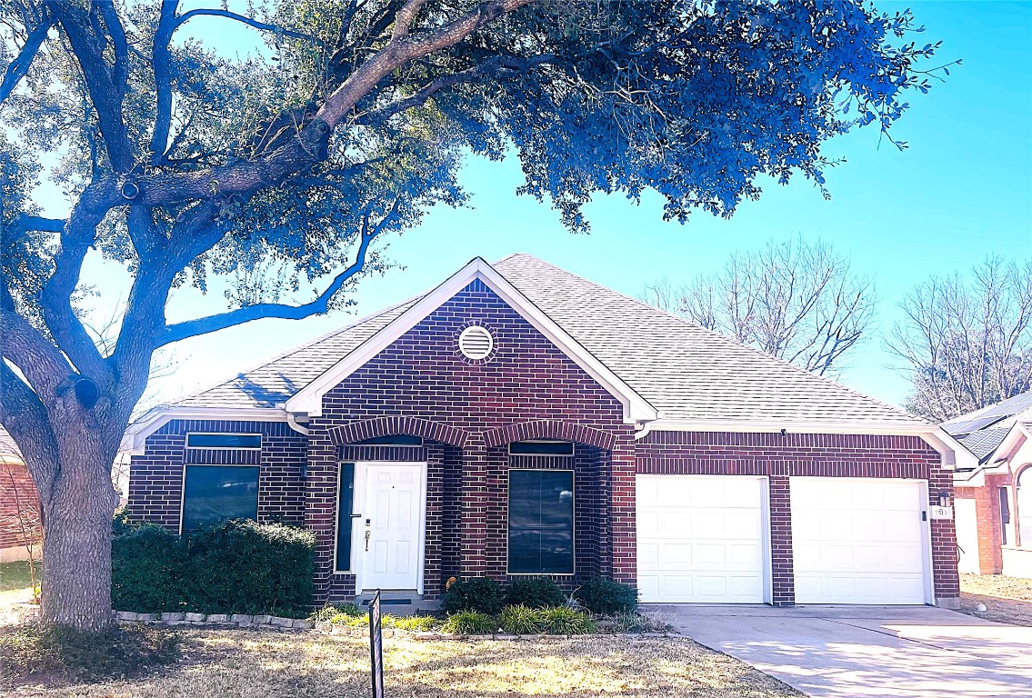 Ranch-style house featuring a shingled roof, an attached garage, concrete driveway, and brick siding