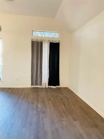 an empty room with wooden floor and fan