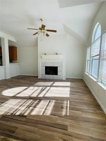 a view of an empty room with wooden floor fireplace and a window