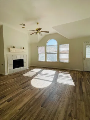 a view of empty room with wooden floor and fan