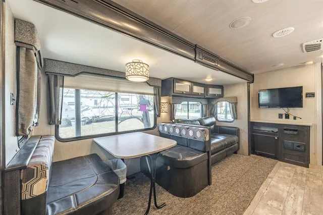 a living room with furniture a flat screen tv and floor to ceiling window