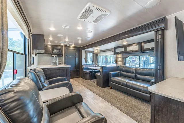 a living room with furniture ceiling fan and a large window