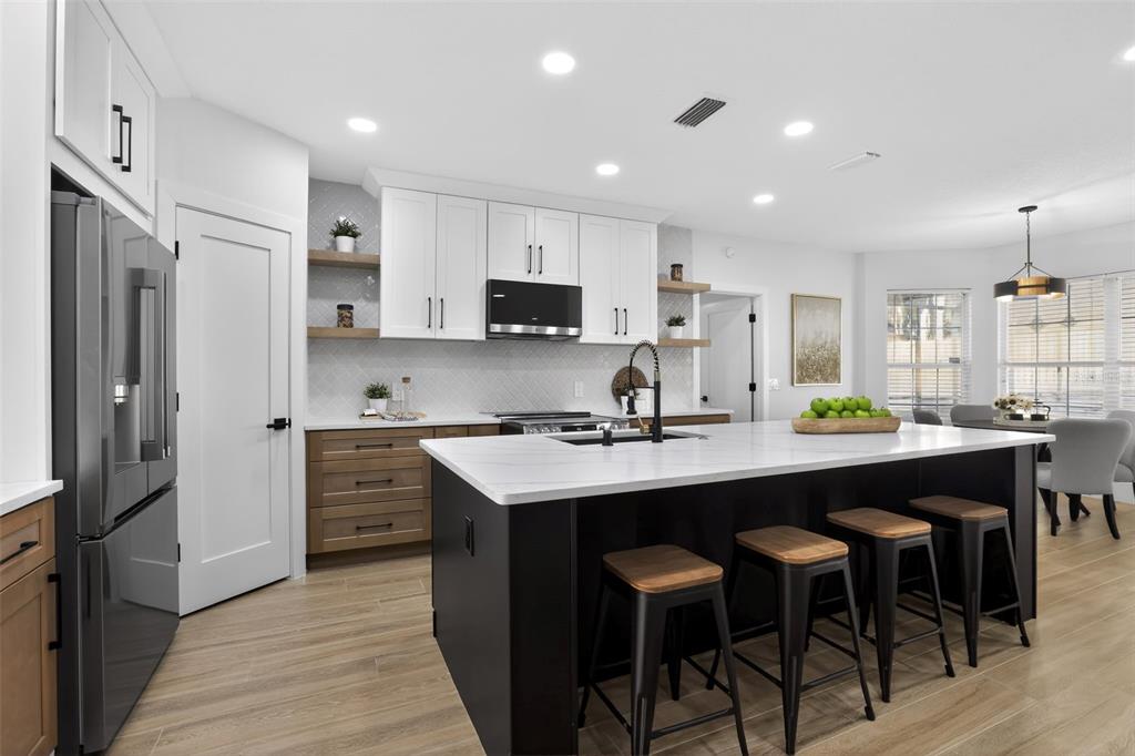 1815 Seneca Boulevard Winter Springs, FL 32708 - Photo 12 of 32 a kitchen with stainless steel appliances granite countertop a sink a stove a refrigerator and a dining table with wooden floor