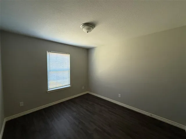 an empty room with wooden floor and window