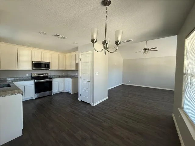 a kitchen with stainless steel appliances granite countertop a refrigerator a sink dishwasher a stove and white countertops with wooden floor