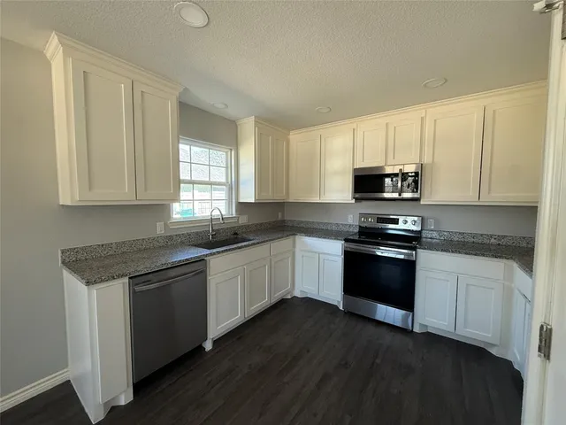 a kitchen with granite countertop white cabinets and black appliances
