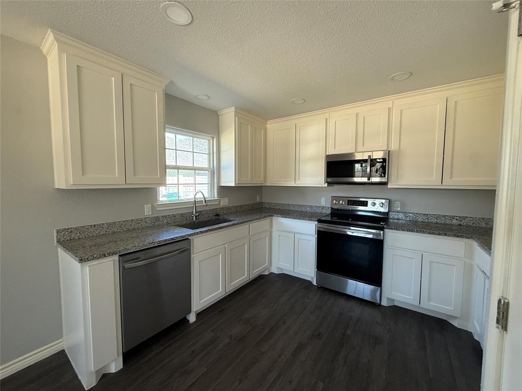 705 South Binkley Street Sherman, TX 75092 - Photo 8 of 22 a kitchen with granite countertop white cabinets and black appliances
