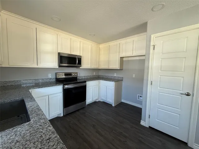 a kitchen with a refrigerator stove and white cabinets